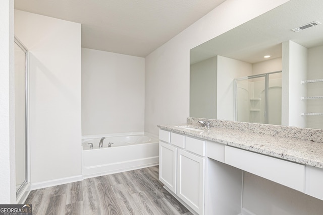 bathroom with a garden tub, visible vents, a shower stall, vanity, and wood finished floors