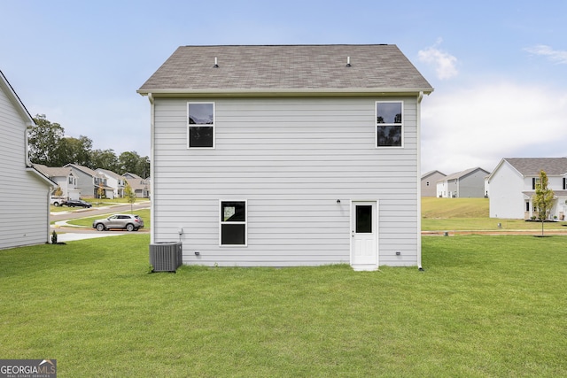 rear view of property with a yard, roof with shingles, and cooling unit