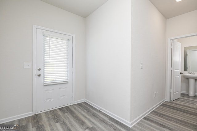 doorway with a sink, baseboards, and wood finished floors