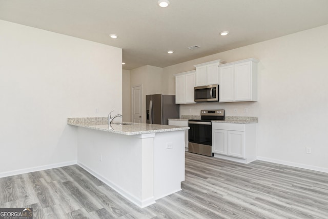 kitchen with appliances with stainless steel finishes, light wood-type flooring, a sink, and white cabinets