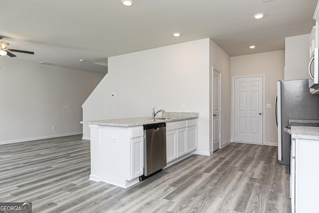 kitchen with appliances with stainless steel finishes, white cabinetry, a peninsula, and light wood finished floors