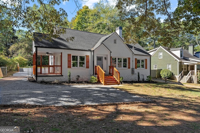 view of front facade featuring covered porch, a shingled roof, a chimney, and brick siding