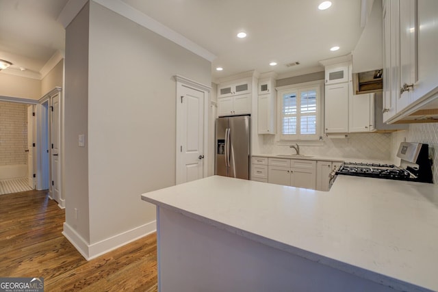 kitchen featuring stainless steel appliances, light countertops, backsplash, ornamental molding, and a sink