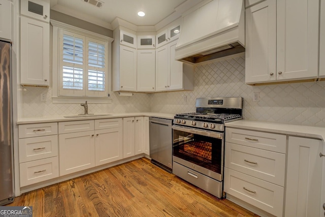 kitchen featuring stainless steel appliances, a sink, light countertops, light wood-type flooring, and custom range hood