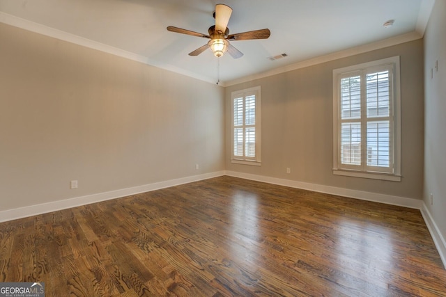 spare room with dark wood-style flooring, visible vents, crown molding, and baseboards