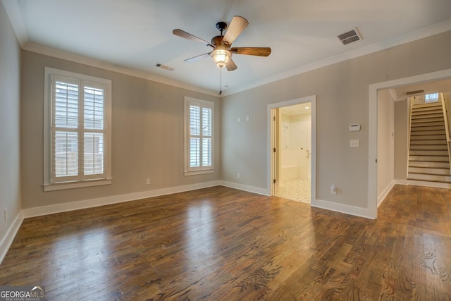 empty room featuring stairs, visible vents, dark wood finished floors, and ornamental molding