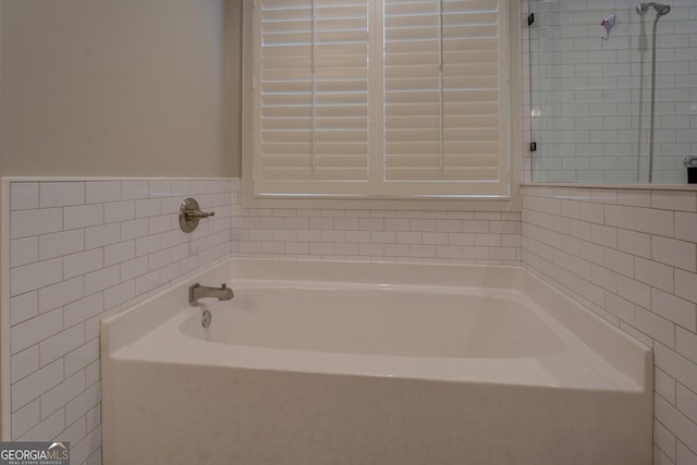 bathroom with a garden tub and tile walls