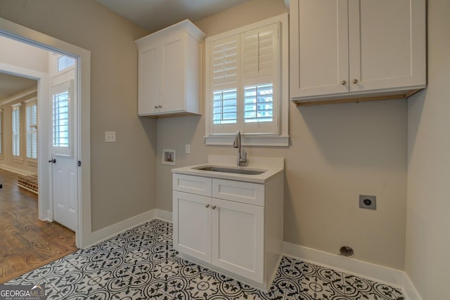 laundry room featuring cabinet space, baseboards, a sink, washer hookup, and electric dryer hookup