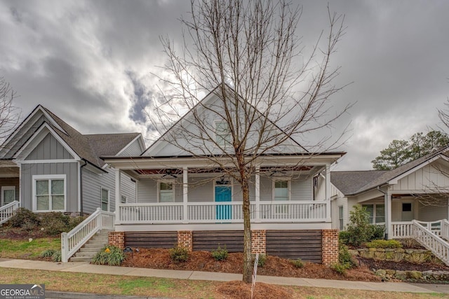 bungalow-style house featuring board and batten siding, covered porch, and stairway