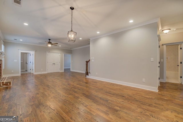 unfurnished living room with a fireplace, visible vents, ornamental molding, wood finished floors, and stairs