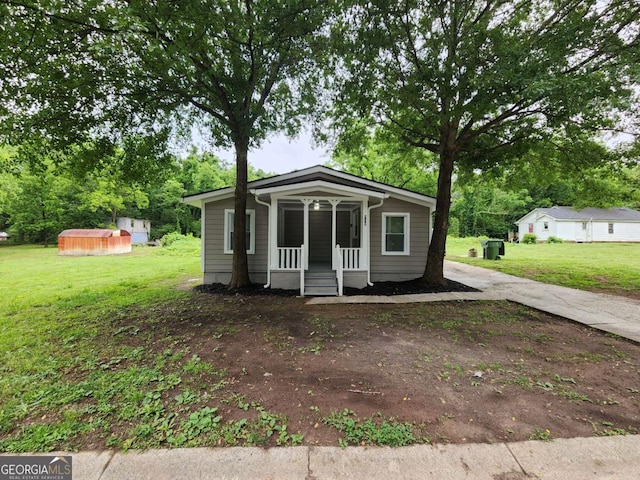 bungalow featuring an outdoor structure, a storage unit, a porch, and a front yard