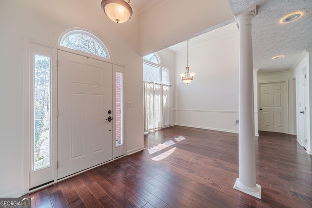 foyer entrance with dark wood-type flooring, ornate columns, and ornamental molding