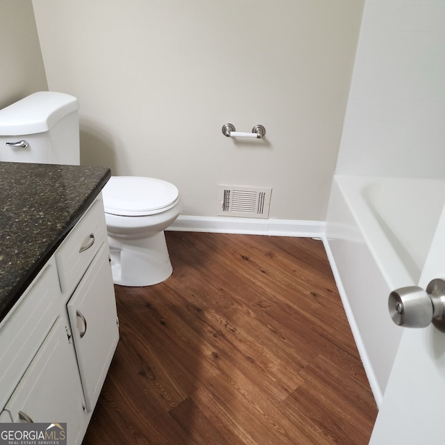 bathroom featuring visible vents, toilet, wood finished floors, baseboards, and vanity