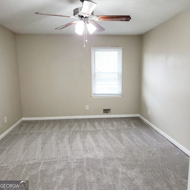 carpeted empty room with visible vents, ceiling fan, and baseboards