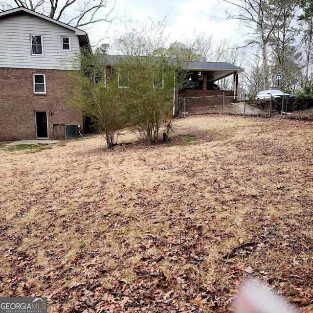 view of yard featuring a carport, central AC unit, and fence