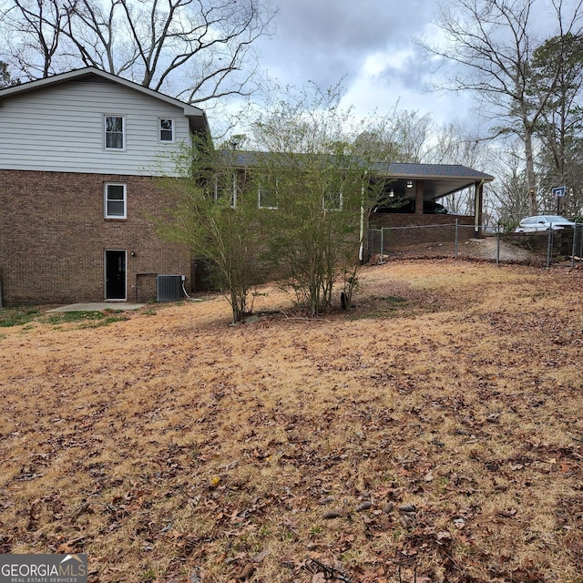 back of house featuring cooling unit, brick siding, and fence