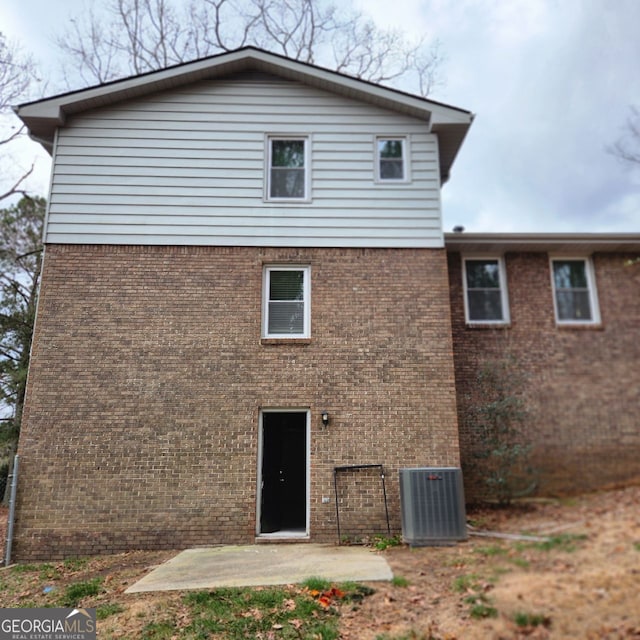 rear view of property with brick siding, central AC unit, and a patio