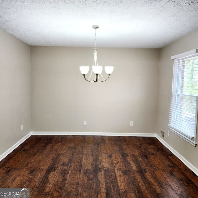 unfurnished room with dark wood finished floors, a textured ceiling, baseboards, and a chandelier