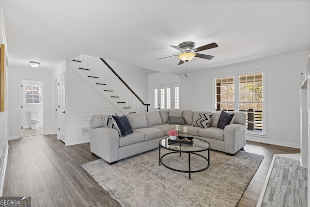 living room with stairway, visible vents, dark wood-style flooring, and ornamental molding