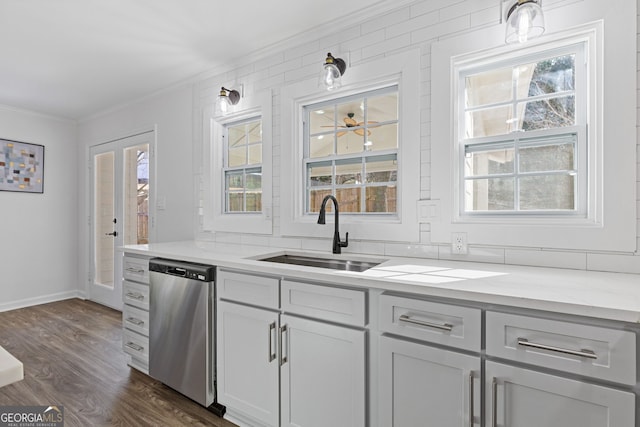 kitchen featuring crown molding, dark wood finished floors, a sink, dishwasher, and baseboards