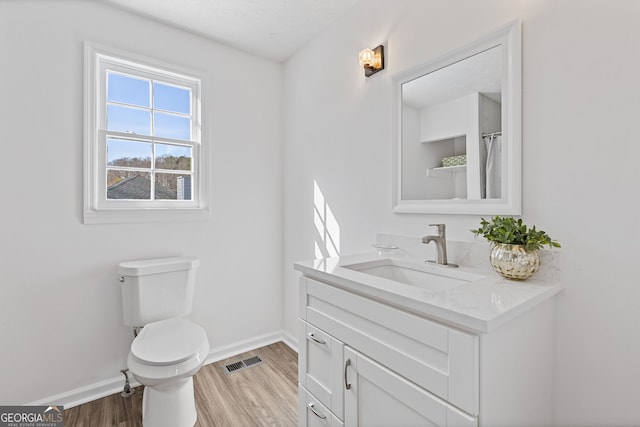 bathroom featuring visible vents, toilet, vanity, wood finished floors, and baseboards