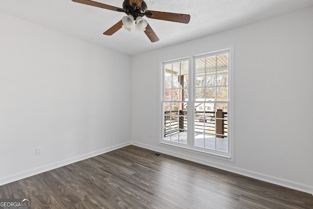 spare room featuring ceiling fan, a textured ceiling, visible vents, baseboards, and dark wood finished floors