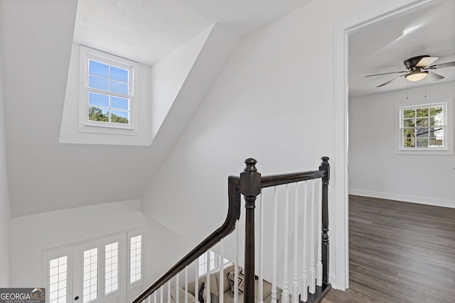 staircase with ceiling fan, wood finished floors, and baseboards