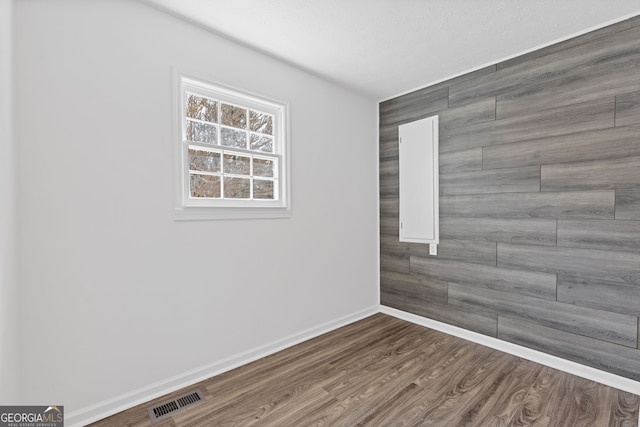 empty room featuring dark wood-style floors, visible vents, and baseboards