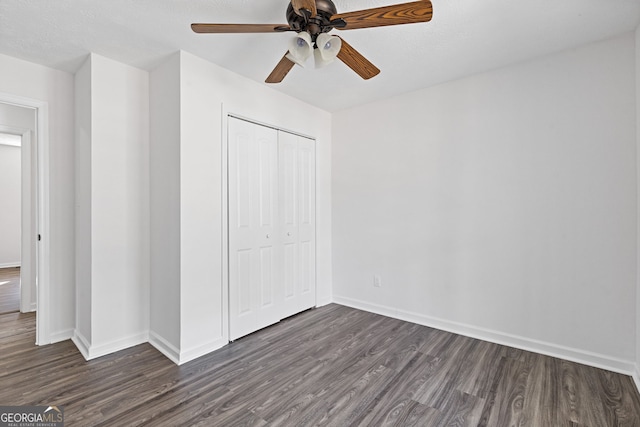 unfurnished bedroom featuring dark wood-style floors, ceiling fan, baseboards, and a closet