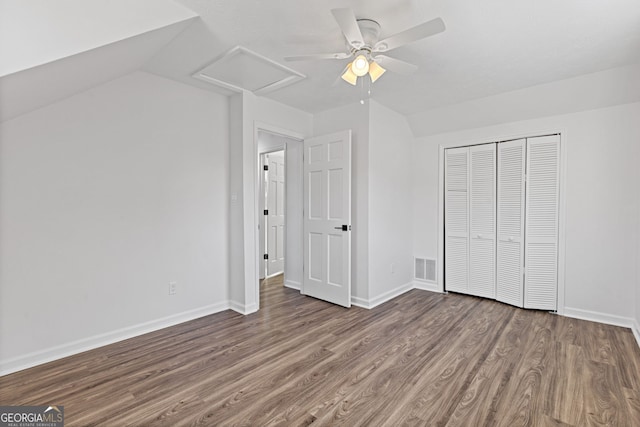 unfurnished bedroom with a closet, visible vents, attic access, wood finished floors, and baseboards