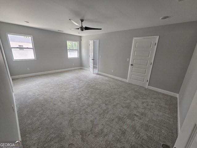 carpeted spare room featuring ceiling fan, visible vents, and baseboards