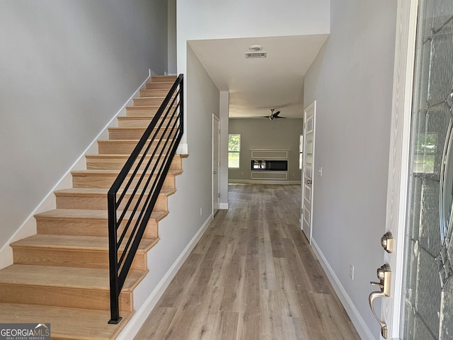 foyer entrance with wood finished floors, stairway, a glass covered fireplace, and visible vents