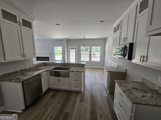 kitchen featuring a peninsula, appliances with stainless steel finishes, a sink, and light stone countertops