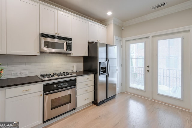 kitchen featuring visible vents, dark countertops, stainless steel appliances, crown molding, and decorative backsplash