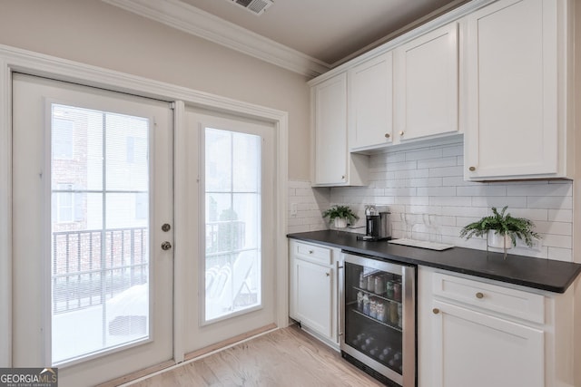 interior space with backsplash, dark countertops, beverage cooler, and ornamental molding