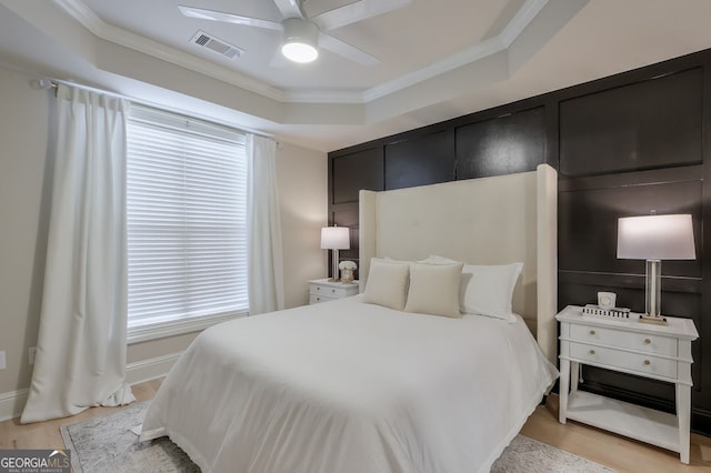 bedroom featuring visible vents, light wood-style floors, and ornamental molding