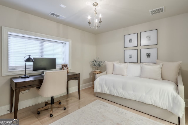 bedroom with a notable chandelier, wood finished floors, visible vents, and baseboards