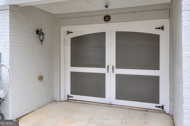 doorway to property with brick siding and a garage