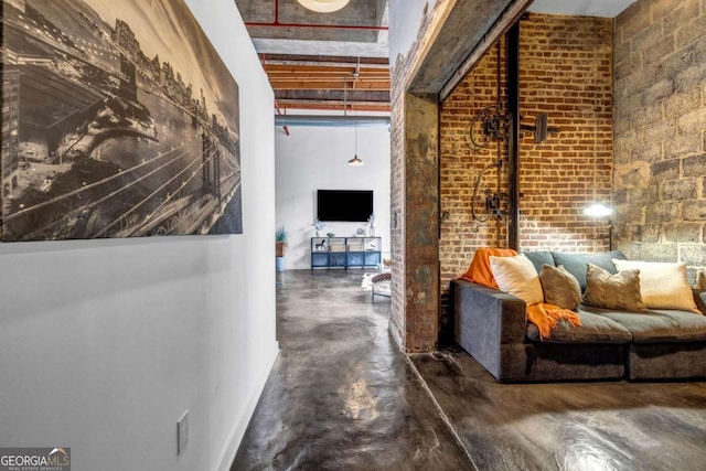 hall featuring finished concrete flooring and brick wall