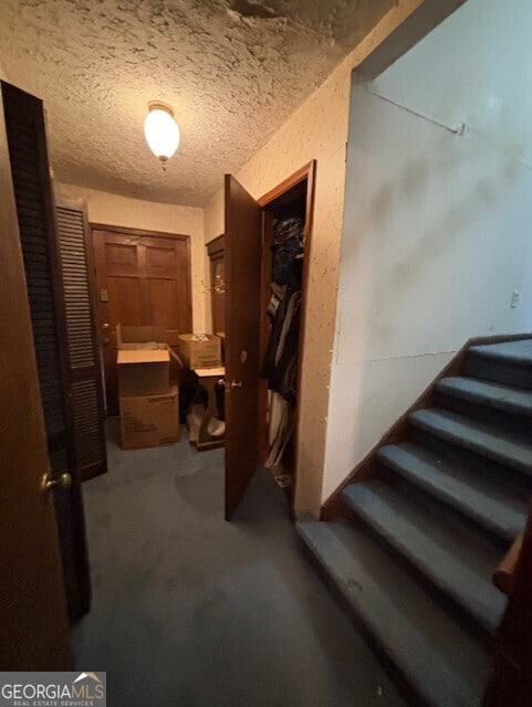 hallway with stairway, carpet flooring, and a textured ceiling