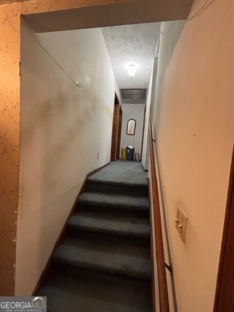 stairs featuring wallpapered walls, visible vents, and a textured ceiling