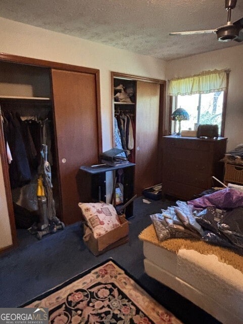 bedroom featuring multiple closets, a textured ceiling, and a ceiling fan