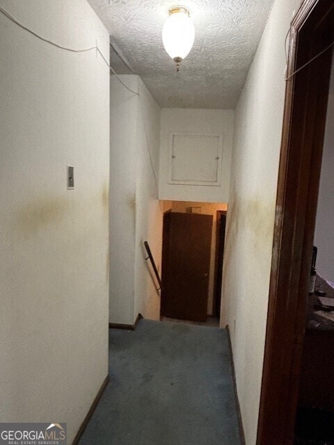 hallway featuring an upstairs landing, carpet floors, and a textured ceiling