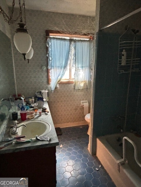 full bathroom featuring wallpapered walls, baseboards, toilet, shower / bathing tub combination, and vanity