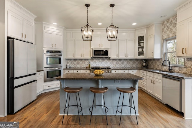 kitchen with a sink, stainless steel appliances, white cabinets, and a center island