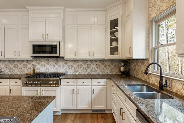 kitchen with dark stone countertops, appliances with stainless steel finishes, white cabinets, and a sink