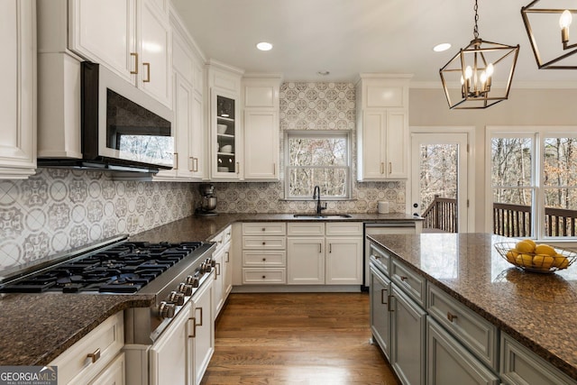 kitchen with a sink, dark wood-style floors, dark stone counters, glass insert cabinets, and white microwave