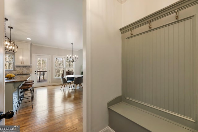 mudroom with wood finished floors, baseboards, an inviting chandelier, recessed lighting, and ornamental molding