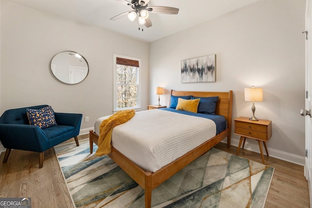 bedroom featuring light wood-style flooring, a ceiling fan, and baseboards