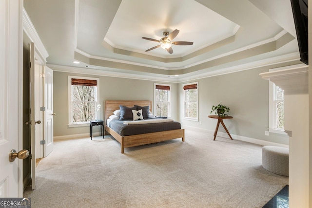 carpeted bedroom featuring multiple windows, a raised ceiling, and baseboards